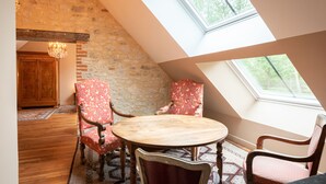 Un coin repas avec une table ronde et quatre chaises, un lustre et un mur en pierre.