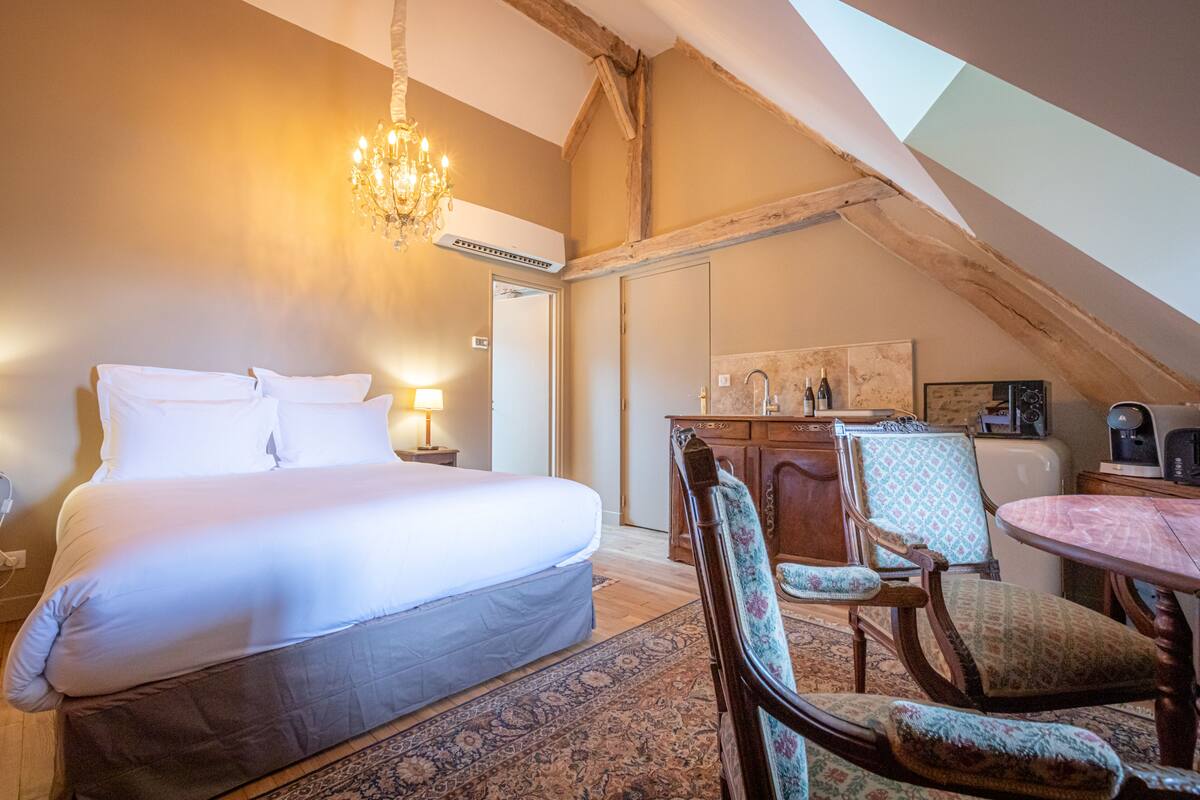 Ein Schlafzimmer mit einem großen Bett, einer Kandelaber, einem Schreibtisch und einem Sessel.