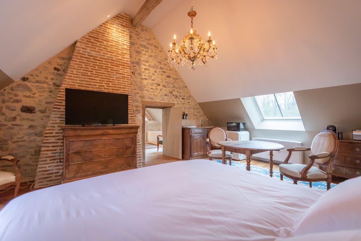 Ein Schlafzimmer mit Steinsandsteinwand, Holzmöbeln, einer Kristallleuchtre und einem Fernseher.