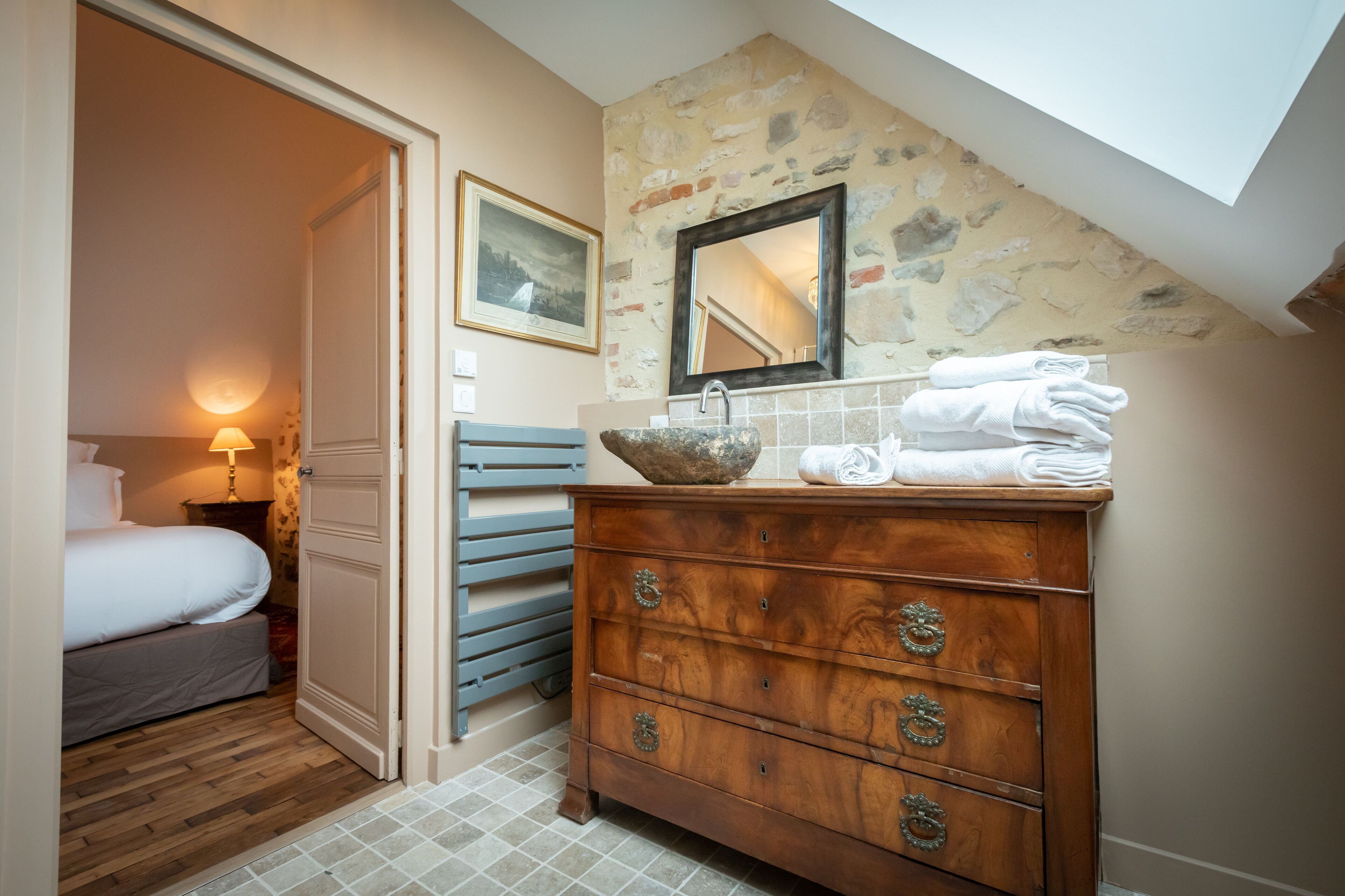A bedroom with a wooden dresser, a mirror, and a bed.