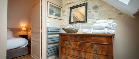 A bedroom with a wooden dresser, a mirror, and a bed.