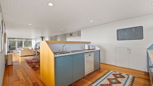 Una cuina moderna amb una illa central, rentaplats integrat i un gran finestral que deixa entrar llum natural.