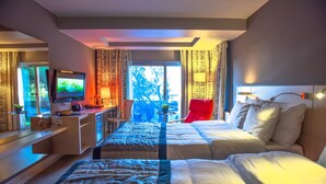 A hotel room with a bed, a desk with a TV, a chair, and a view of the outdoors. - Denizati Plus Hotel (Istanbul)