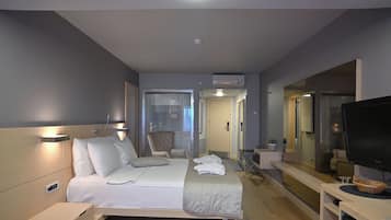 A hotel room with a bed, bedside table, TV, and a mirror.