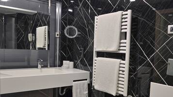 Une salle de bain moderne avec un mur en marbre noir, un lavabo blanc, un miroir, un porte-serviettes et des toilettes.