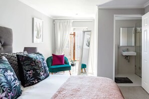 A bedroom with a bed, a green armchair, a sofa, and a bathroom with a sink and shower. - 3 Bedroom Hilltop Home With Spectacular Views (Cape Town)