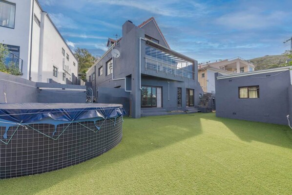 Une maison moderne à deux étages, dotée d’un toit plat, de grandes fenêtres et d’un balcon.