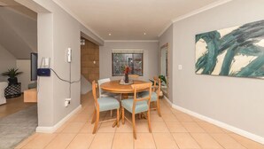A dining area with a round wooden table, four chairs, and a vase with flowers. - Spaciaous 2 Bedroom Bokaap Apartment (Cape Town)