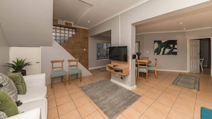 A modern living room with a TV, seating, and a staircase. - Spaciaous 2 Bedroom Bokaap Apartment (Cape Town)