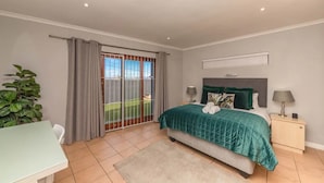 A bedroom with a bed, bedside tables, a desk, and a view through a sliding door to a balcony. - Spaciaous 2 Bedroom Bokaap Apartment (Cape Town)