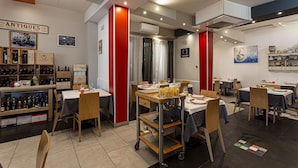 Un restaurante con varias mesas, sillas y una exhibición de vinos.