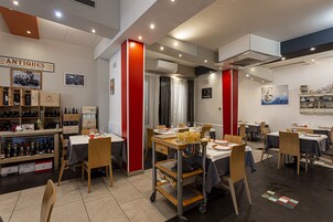 Un restaurante con varias mesas, sillas y una exhibición de vinos.