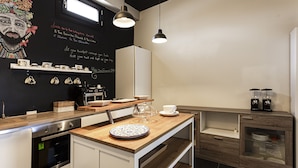 Una cocina moderna con encimera de madera, armarios blancos y un salpicadero negro con detalles decorativos.