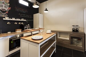 Una cocina moderna con encimera de madera, armarios blancos y un salpicadero negro con detalles decorativos.