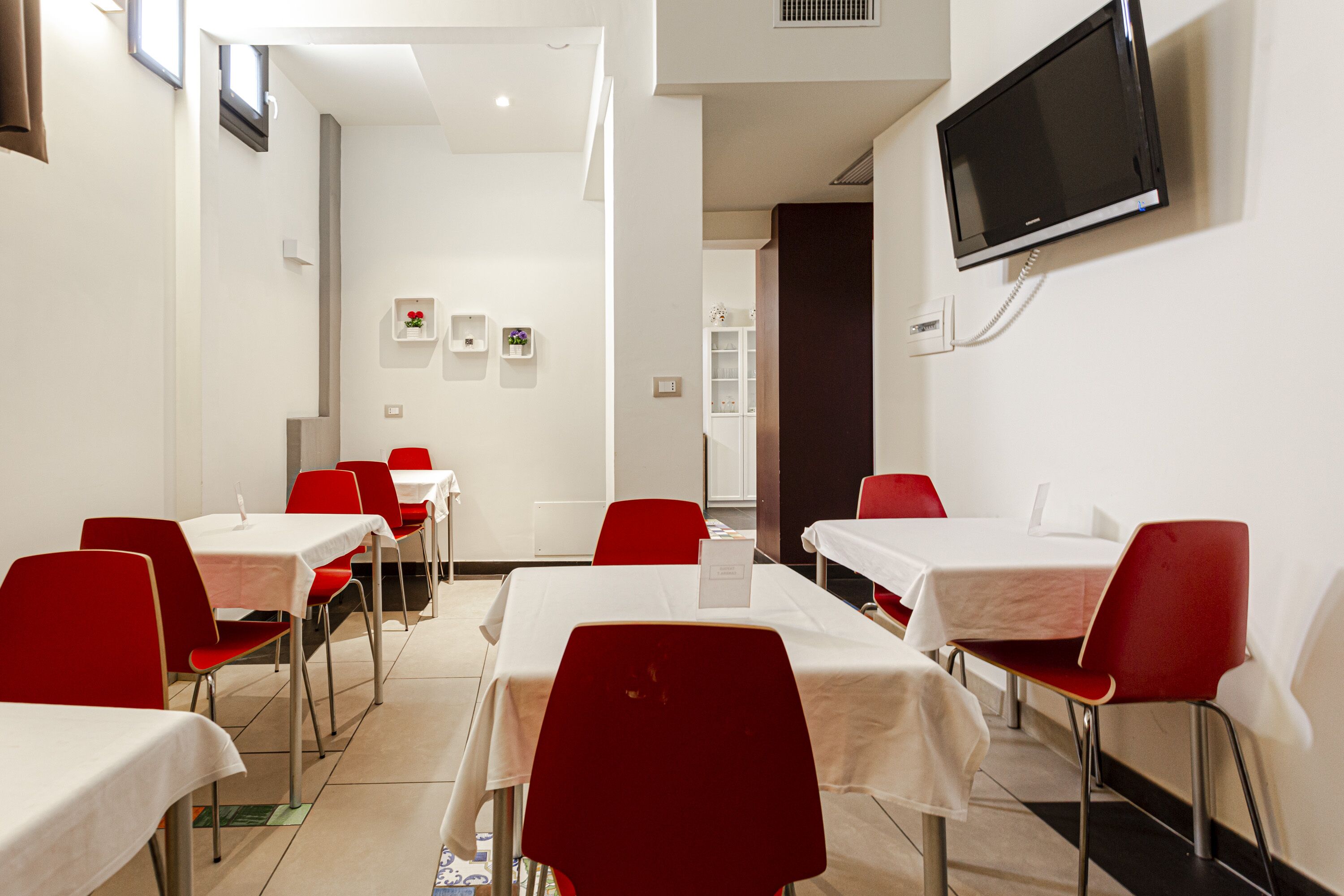 A conference room with tables and chairs, a television mounted on the wall, and a whiteboard.