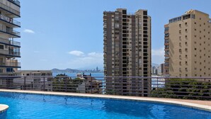 A swimming pool with a view of tall residential buildings and a distant city skyline.