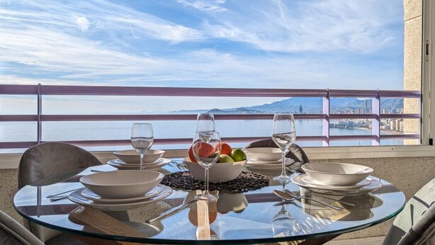 A dining table with a clear view of the sea and mountains in the background.