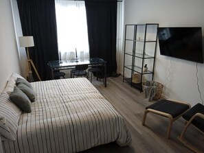 Une chambre d’hôtel comprenant un lit, un bureau, une chaise, une télévision et une bibliothèque.