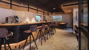 A modern bar area with a wooden counter, bar stools, and a coffee machine. - Hotel La Réserve (St. Niklaus)