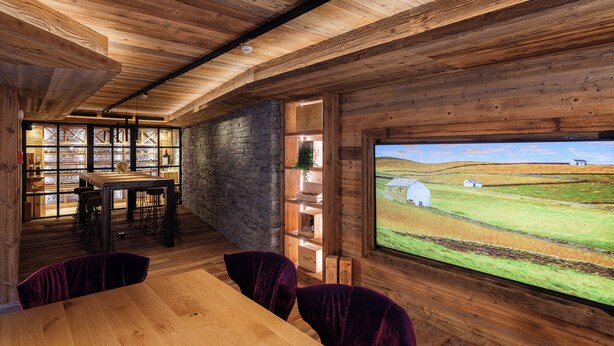 A rustic interior with a wooden ceiling, stone walls, and a large window overlooking a rural landscape. - Hotel La Réserve (St. Niklaus)