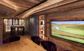 Un interior rústico con techo de madera, paredes de piedra y un ventanal grande con vistas al paisaje rural.