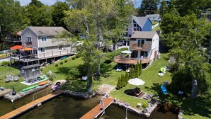 A lakeside property with a dock, a small boat, and a wooden deck. - Waterfront Cottage at Highland Lake w/dock (Winsted)