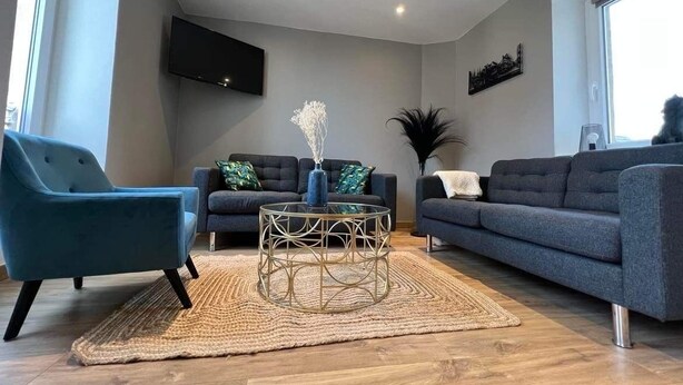 Un salon moderne avec deux canapés, une table basse et un téléviseur fixé au mur.