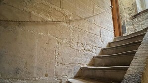 Un escalier en pierre avec une main courante en bois et une corde de sécurité.