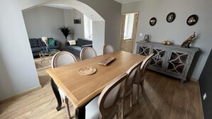 Un coin repas comprenant une table en bois, des chaises et un meuble contenant des objets décoratifs.