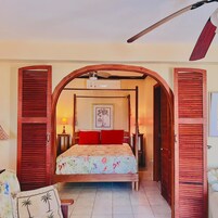 Un dormitorio con cama con dosel, ventilador de techo y un cuadro en la pared.