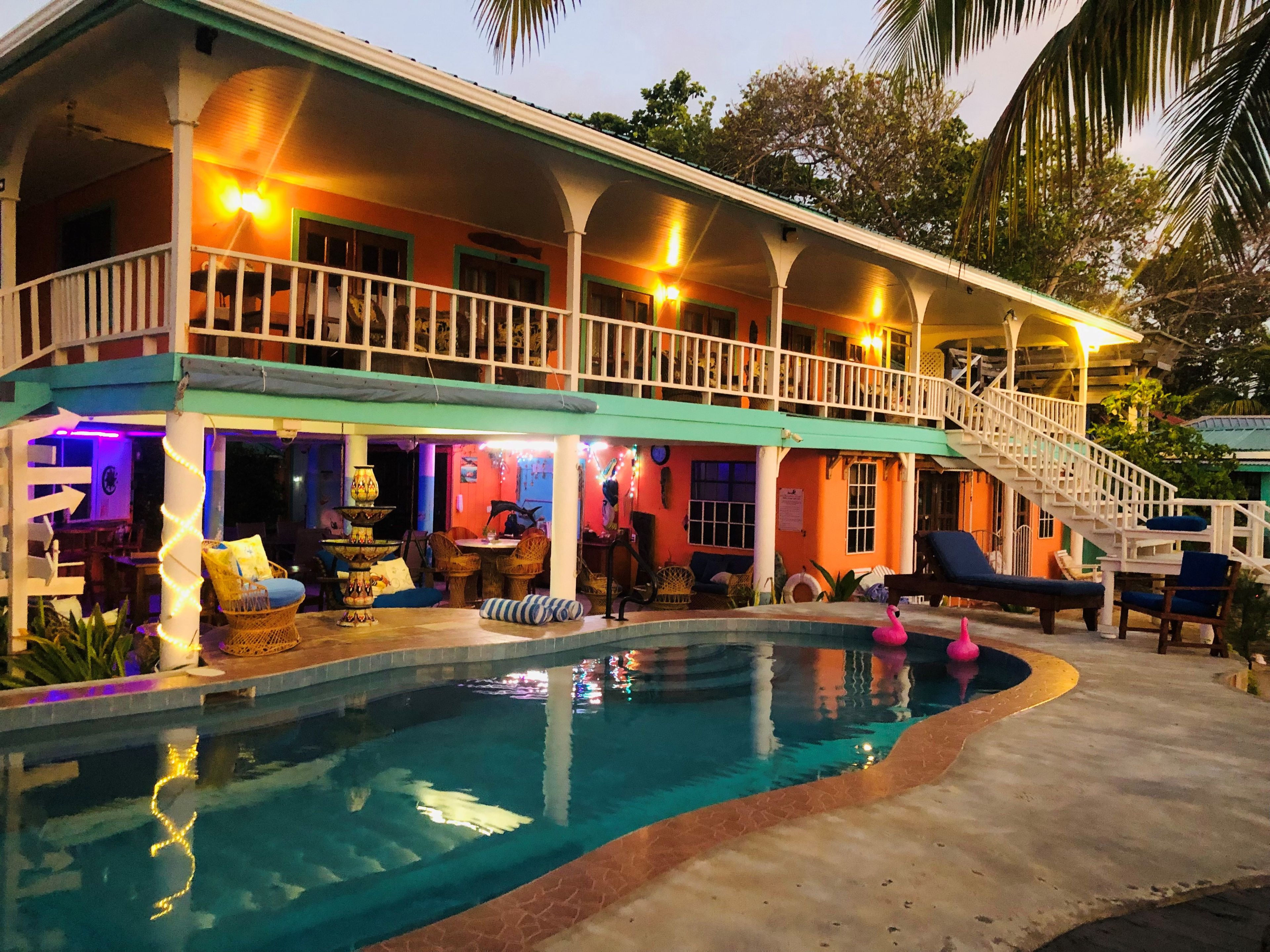Una casa de dos pisos con piscina, zona de estar exterior y escalera que conduce al nivel superior.