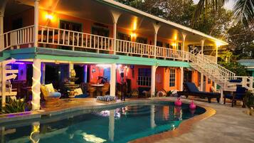 Una casa de dos pisos con piscina, zona de estar exterior y escalera que conduce al nivel superior.