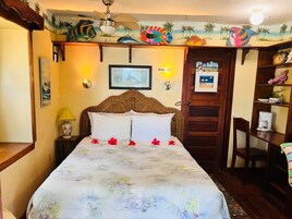 A bedroom with a bed, a nightstand, a lamp, a wall clock, and a door.