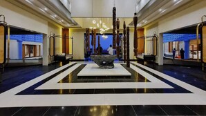 A spacious lobby with a central art installation, a reception desk, and a view of the lobby area.