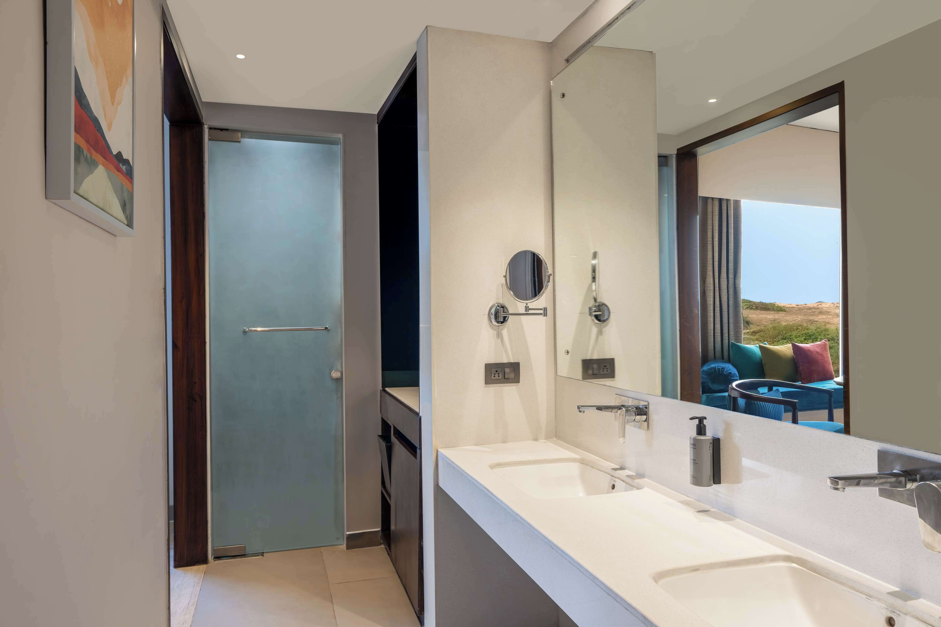 Un baño moderno con un espejo grande, dos lavamanos y una ducha.