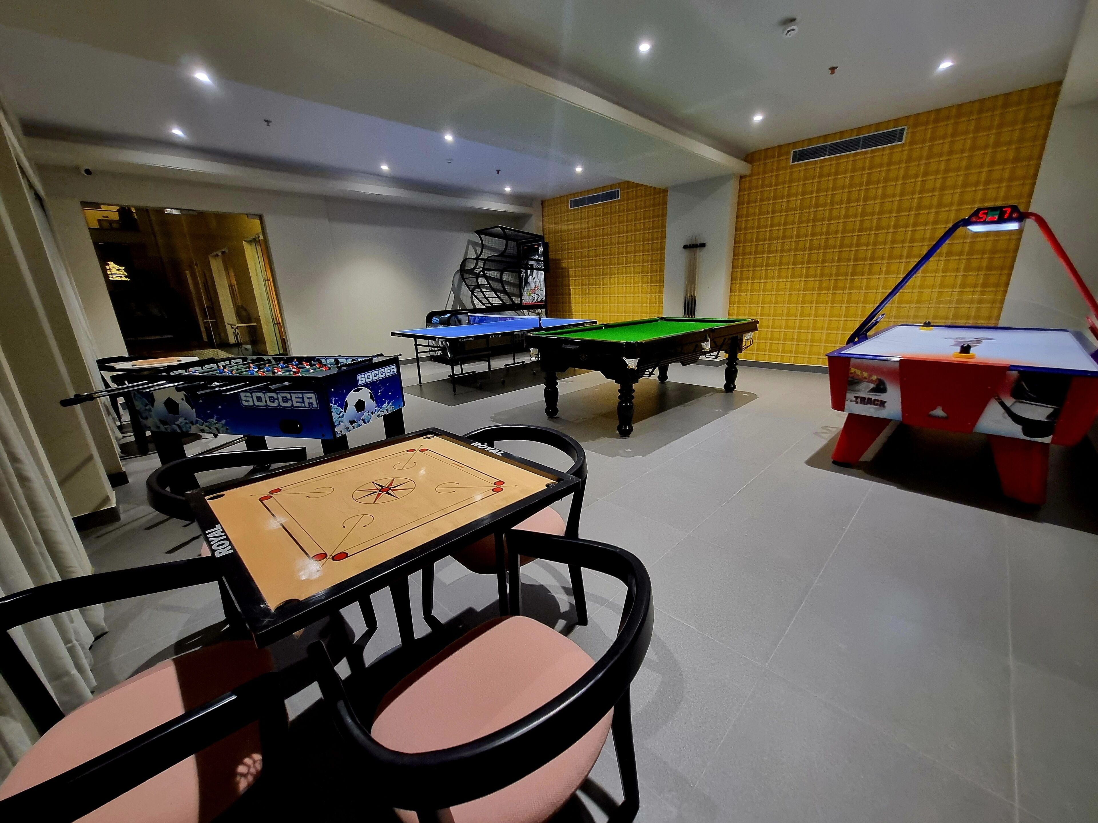 Un espace de loisirs équipé de tables de baby-foot, d’un billard et d’une table de ping-pong.