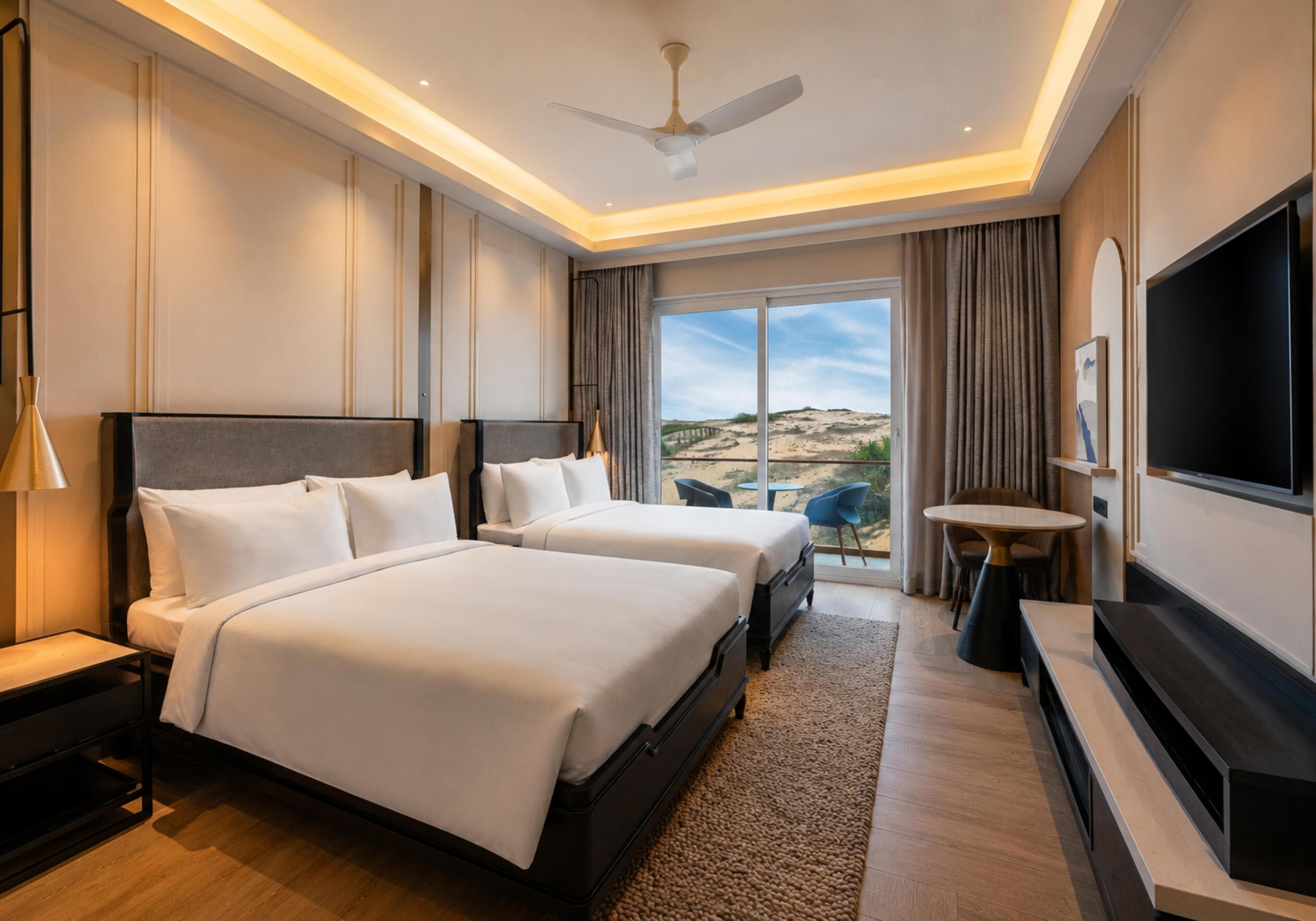 Habitación de hotel con dos camas, televisión, ventilador de techo y vista a la playa.