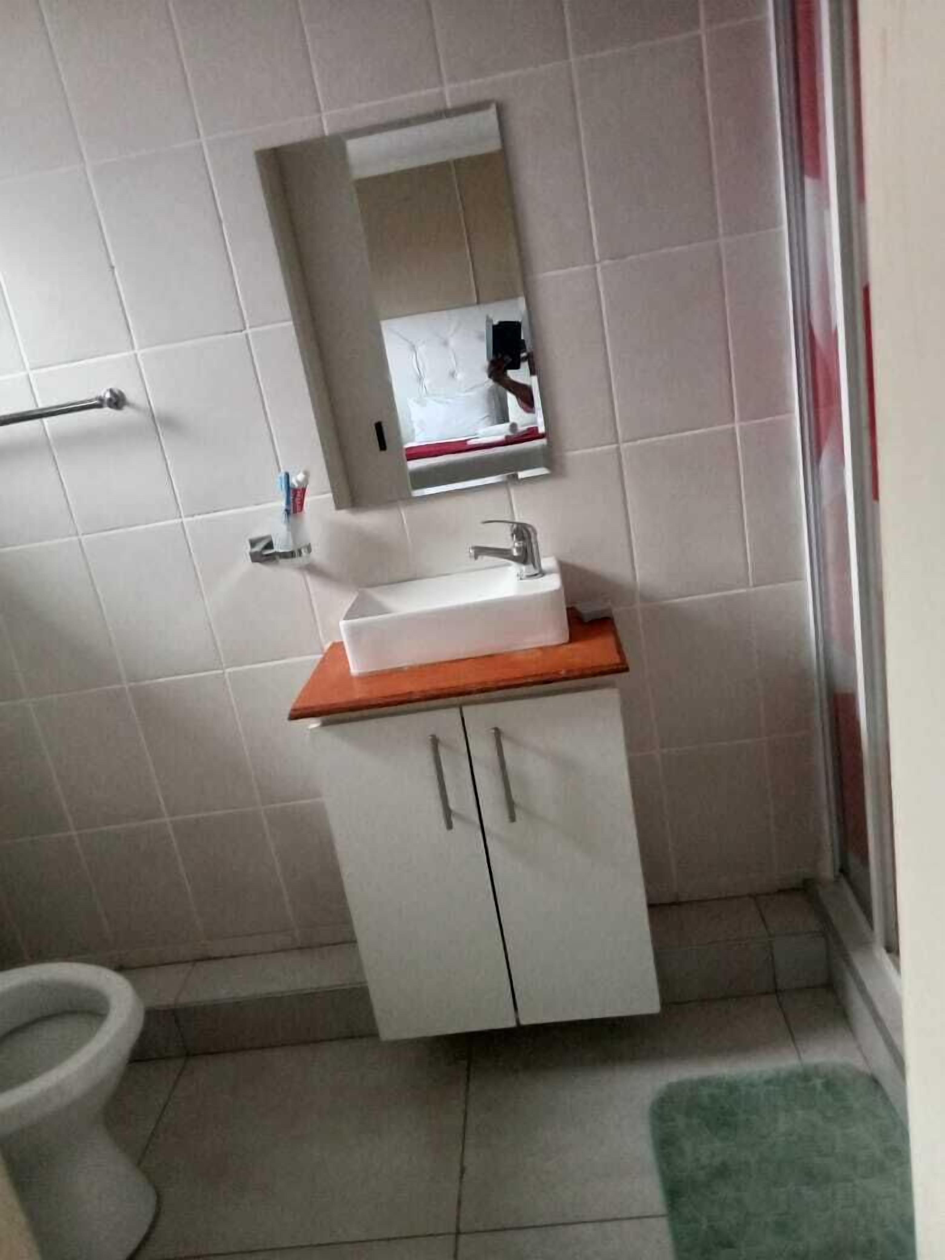 Une petite salle de bain avec un lavabo blanc, un miroir et des toilettes.