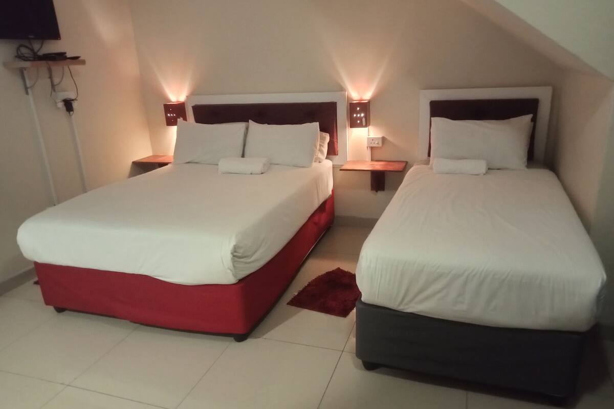 Twee bedden met witte lakens in een kamer met een schuine kap.