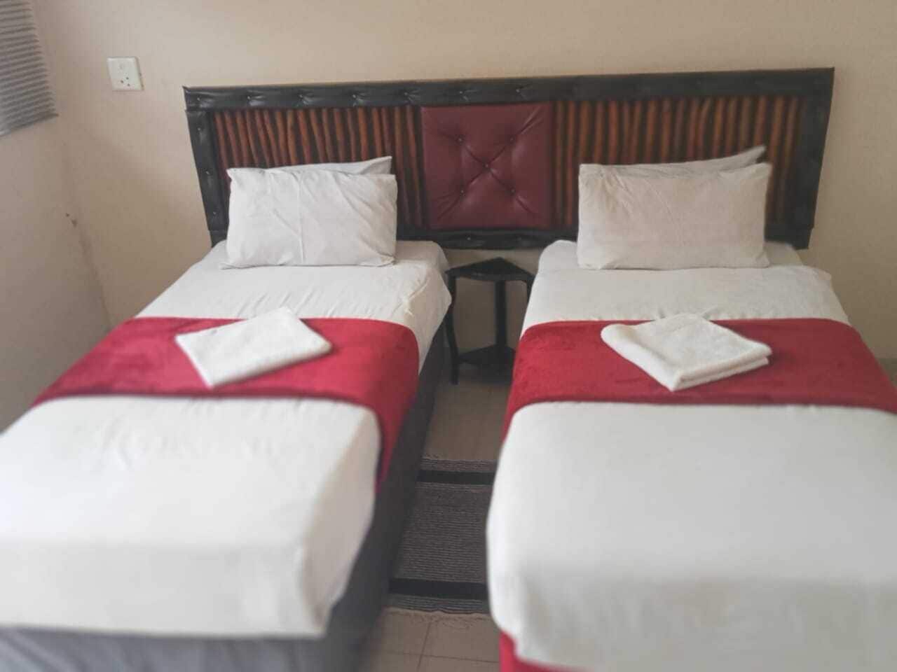 Une chambre d’hôtel avec deux lits simples, chacun recouvert d’une courtepointe rouge et blanche et agrémenté d’oreillers blancs.