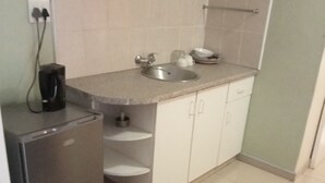Eine kleine Küche mit Spüle, Kaffeemaschine und Kühlschrank.