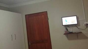 Una habitación con puerta de madera, televisión montada en la pared y techo con textura.