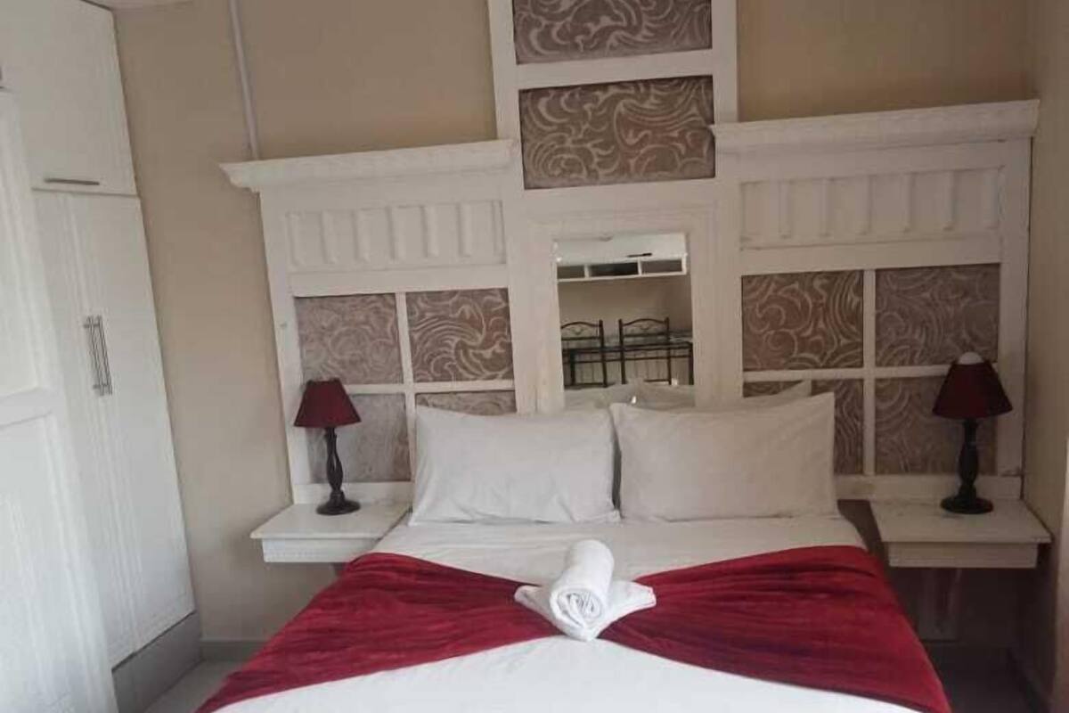 Een hotelkamer met een groot bed, een wit hoofdeinde en twee nachtkastjes met lampen.