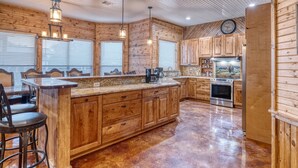 A spacious kitchen with wooden cabinetry, a large island, and a stainless steel oven. - Tatanka @ Frio Premier Rental Homes (Concan)