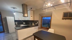 Una cuina moderna amb armaris blancs, un taulell negre, forn integrat i una finestra amb vista a l'exterior.