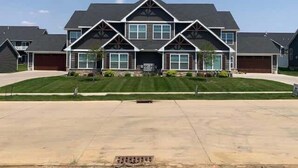 A two-story residential house with a symmetrical facade, large windows, and a central entrance. - Main Floor Cozy 2 Bedroom Condo with a master suite in Bettendorf (Bettendorf)