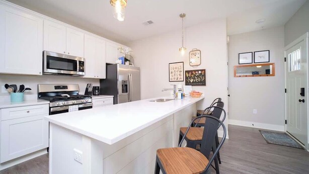 A modern kitchen with white cabinetry, stainless steel appliances, and a central island with bar stools. - Main Floor Cozy 2 Bedroom Condo with a master suite in Bettendorf (Bettendorf)