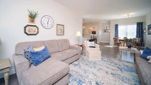 A living room with a sofa, a coffee table, and a dining area with a table and chairs. - Main Floor Cozy 2 Bedroom Condo with a master suite in Bettendorf (Bettendorf)