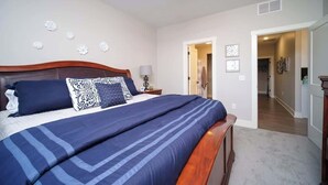 A bedroom with a large bed, a wooden headboard, and a nightstand with a lamp. - Main Floor Cozy 2 Bedroom Condo with a master suite in Bettendorf (Bettendorf)