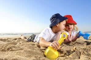 Two children playing with sand toys on a beach. - Fedora Hotel (Rimini)